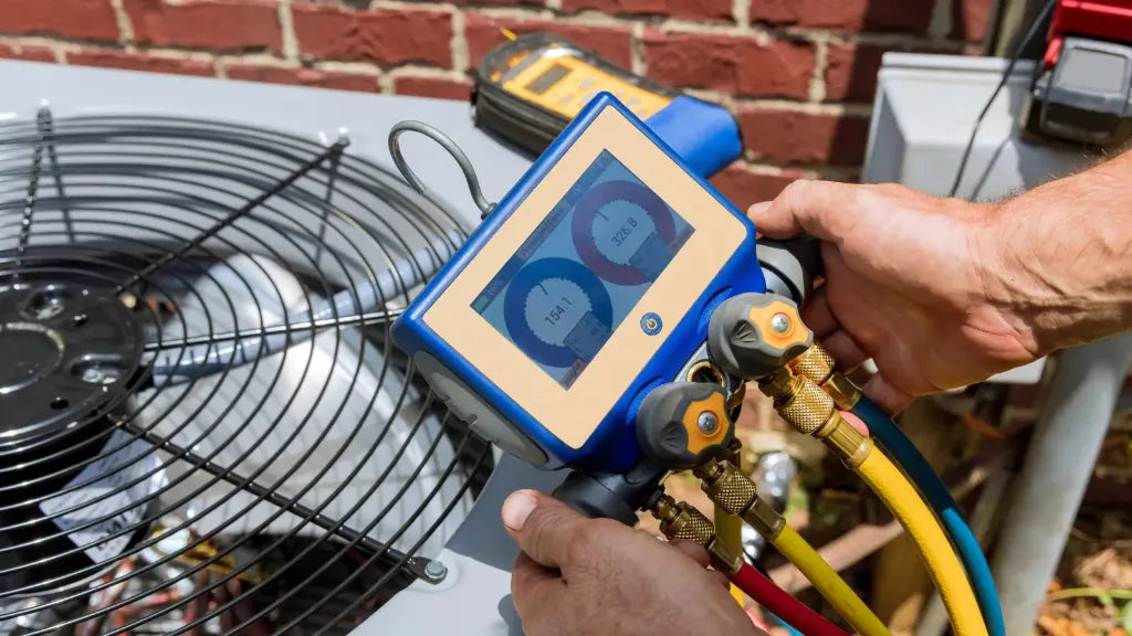 HVAC technician using gauges to test refrigerant pressure on an outdoor air conditioning unit during cooling system service.