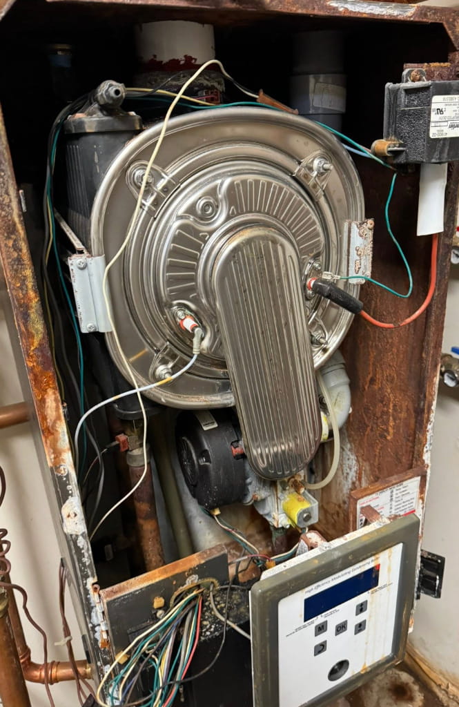 Open boiler system with internal components exposed during professional heating repair, maintenance, and inspection service.