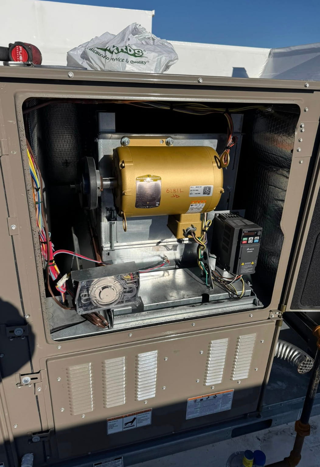 Open commercial HVAC unit showing internal components during professional repair, maintenance, and system inspection.
