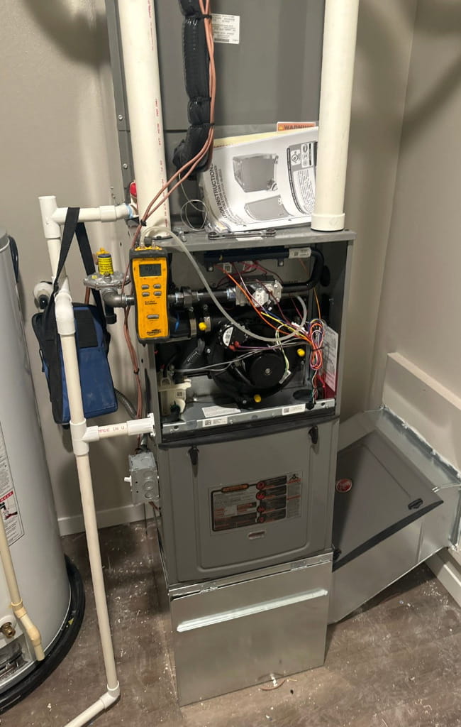 Open residential furnace being inspected during heating system repair, maintenance, and tune-up service.