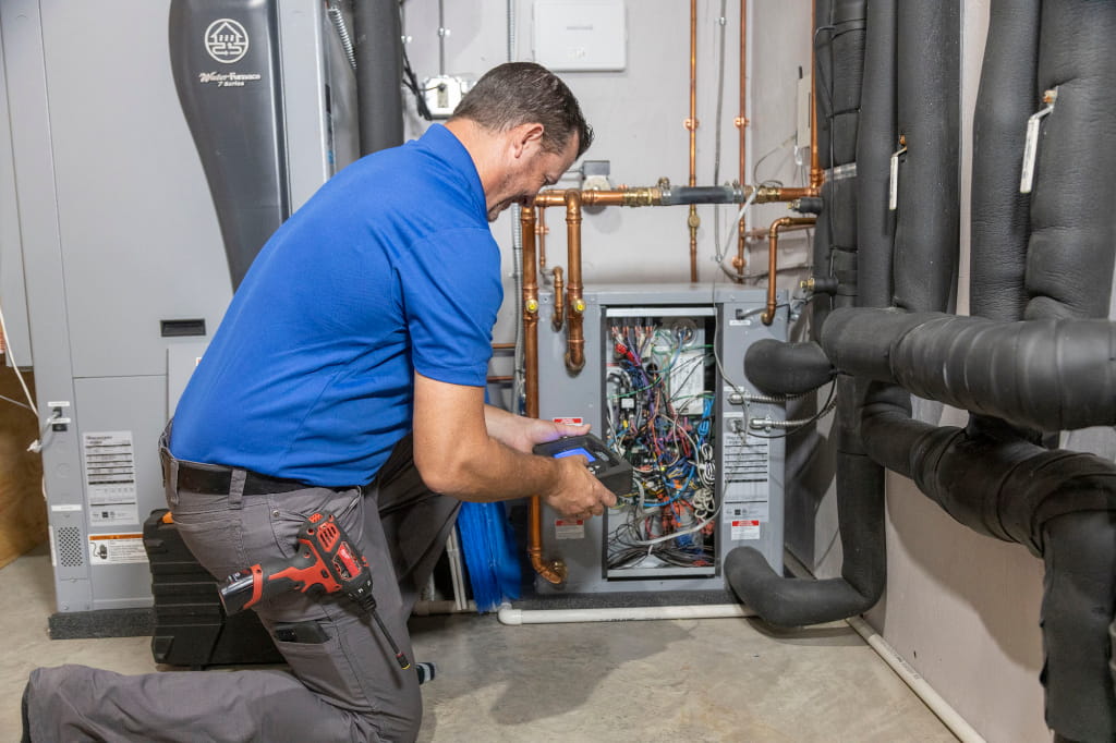 HVAC technician inspecting and servicing an indoor heating and cooling system to improve performance, safety, and efficiency.