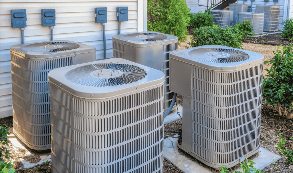 Multiple outdoor air conditioning units installed beside a residential building for reliable cooling and indoor comfort.