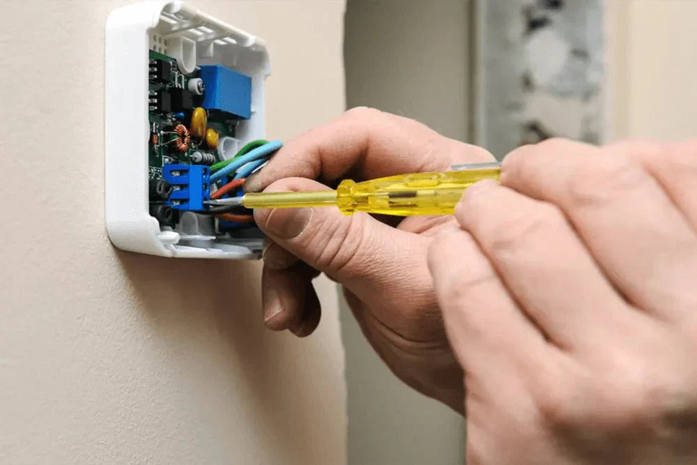 Close-up of a technician wiring a thermostat for an HVAC system upgrade and improved indoor comfort.