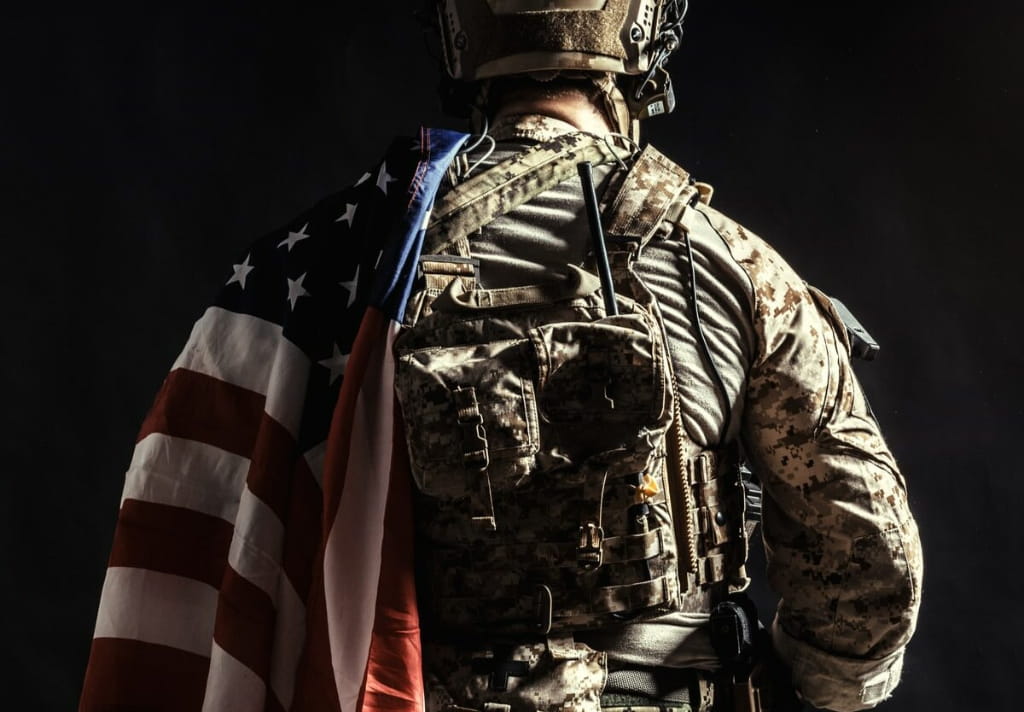 Veteran standing with an American flag, representing military appreciation and service discounts from Wehle Good Heating and Cooling LLC.